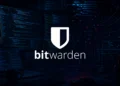 Dark cyberpunk-style developer workspace with multiple monitors displaying code in a dimly lit environment, featuring Bitwarden logo